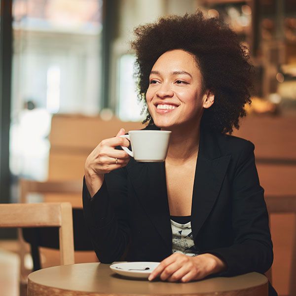 Woman at coffee shop smiling and holding coffee cup